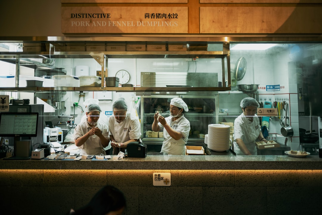 An experienced mentor works with a new team member during staff training for global cuisines in a busy restaurant setting
