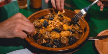 A spice vendor in Marrakech souk surrounded by colorful Moroccan cuisine ingredients