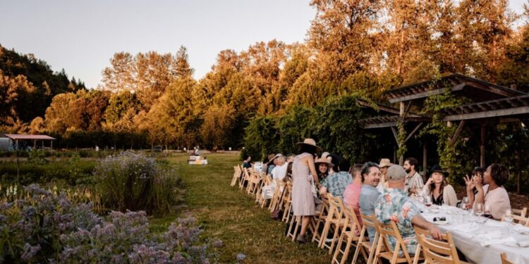 Essensbereich im Freien NYC 8 Gärten zum Buchen - GUSTOwebzine Lange Gartenparty im Freien oder Hochzeitsempfang mit einem langen Gastetisch unter einer Holzlaube, während Herbstbäume im Hintergrund glühen