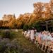 Essensbereich im Freien NYC 8 Gärten zum Buchen - GUSTOwebzine Lange Gartenparty im Freien oder Hochzeitsempfang mit einem langen Gastetisch unter einer Holzlaube, während Herbstbäume im Hintergrund glühen