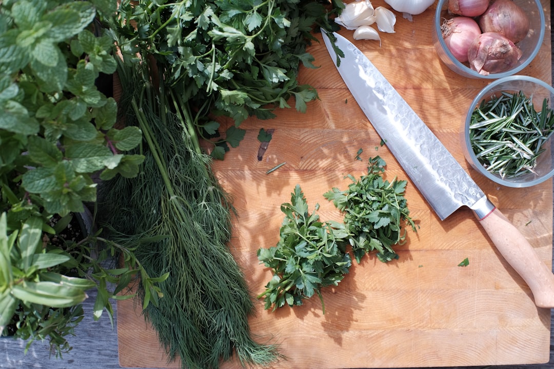 A person rolling and slicing fresh basil using knife skills to create a chiffonade cut