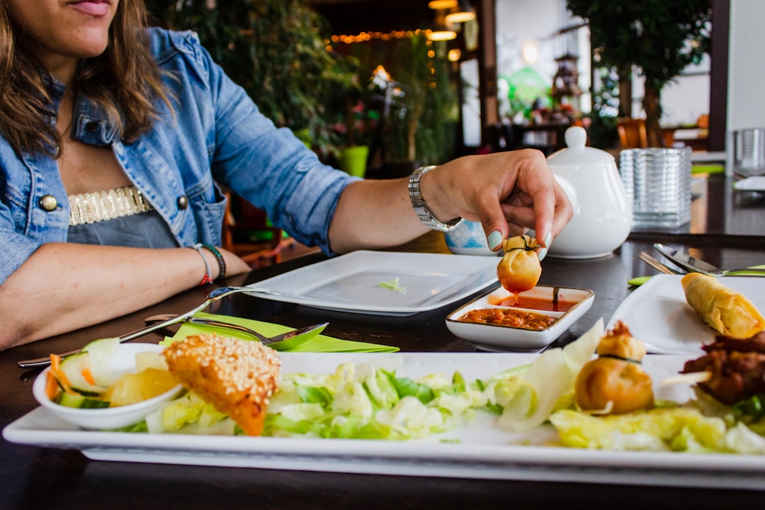 A person adds small bowls of global spreads and fermented toppings to complete a vibrant summer grazing board