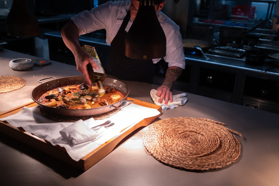 A person serving a Moroccan fish tagine in a rich Moroccan chermoula marinade with preserved lemon and fresh herbs.