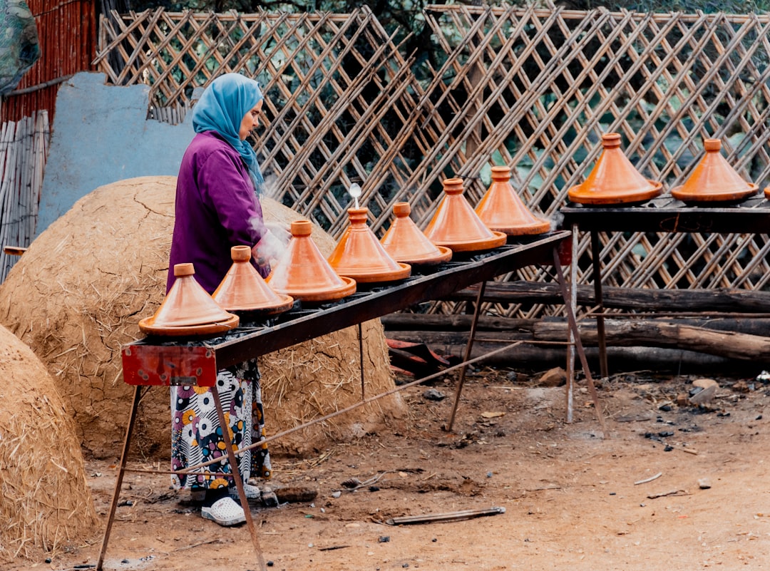 Un cocinero casero preparando braises lentos en una tajine tradicional de barro con especias aromáticas y cordero