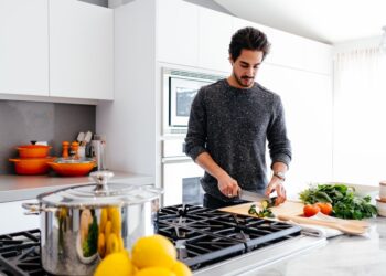 Een professionele chef die vers peterselie fijnhakt om een klassieke groene saus op een houten aanrecht klaar te maken