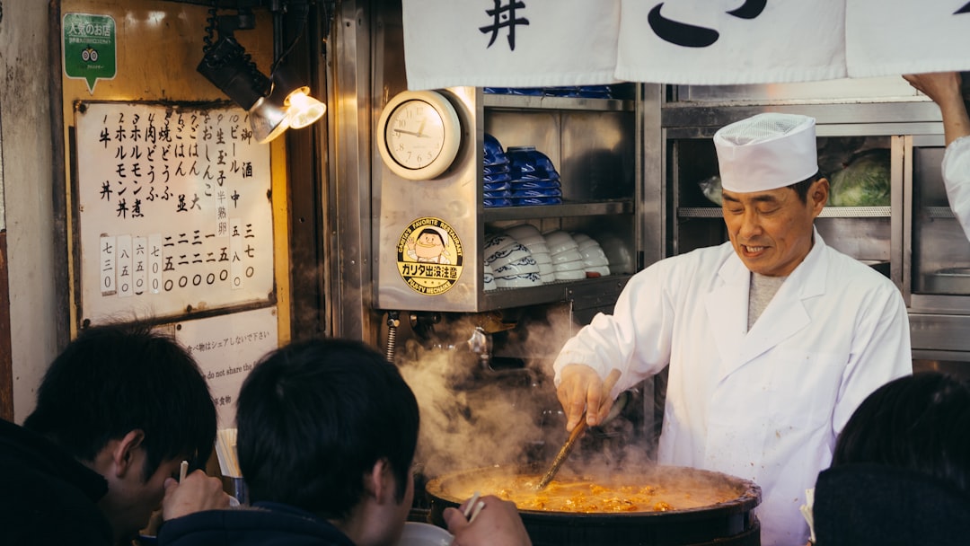 A professional chef carefully preparing food in traditional clay vessels at a busy restaurant kitchen