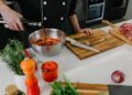 Un chef batiendo los básicos del marinado, incluyendo aceite, cítricos y hierbas frescas en un gran tazón de cerámica