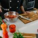 A chef whisking together marinade basics including oil, citrus, and fresh herbs in a large ceramic bowl