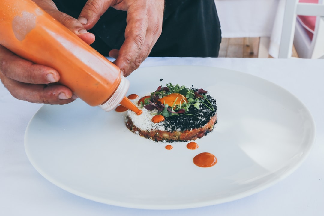 A chef finishing a plate of vibrant grain salads with edamame and sesame, ready to serve cold