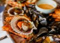 A chef carefully plates a fresh seafood dish as part of resort menus designed for peak coastal season guests