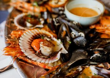 Een chef serveert voorzichtig een vers zeevruchtengerecht op als onderdeel van menukaarten van resorts ontworpen voor piektoeristenperiodes aan de kust