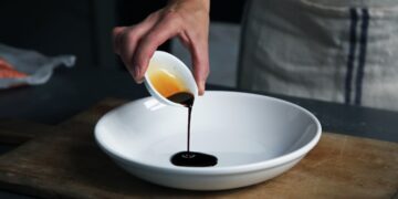 chef-pouring-aged-vinegar-dish-unsplash - GUSTOwebzine A chef carefully drizzling aged vinegar over a finished plate in a professional kitchen