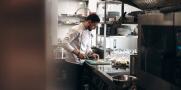 A chef monitors a tray of tomatoes and mushrooms, using key techniques to build deep flavour in a meatless dish.