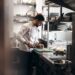 chef-roasting-vegetables-kitchen-unsplash - GUSTOwebzine Un chef supervisa una bandeja de tomates y champiñones, utilizando técnicas clave para construir sabor profundo en un plato sin carne.