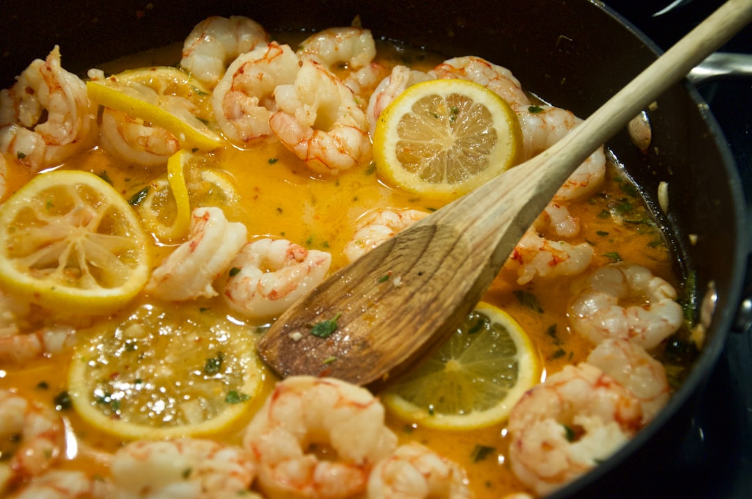 A home cook squeezing fresh lemon juice to balance salt acid and richness in a sautéed dish