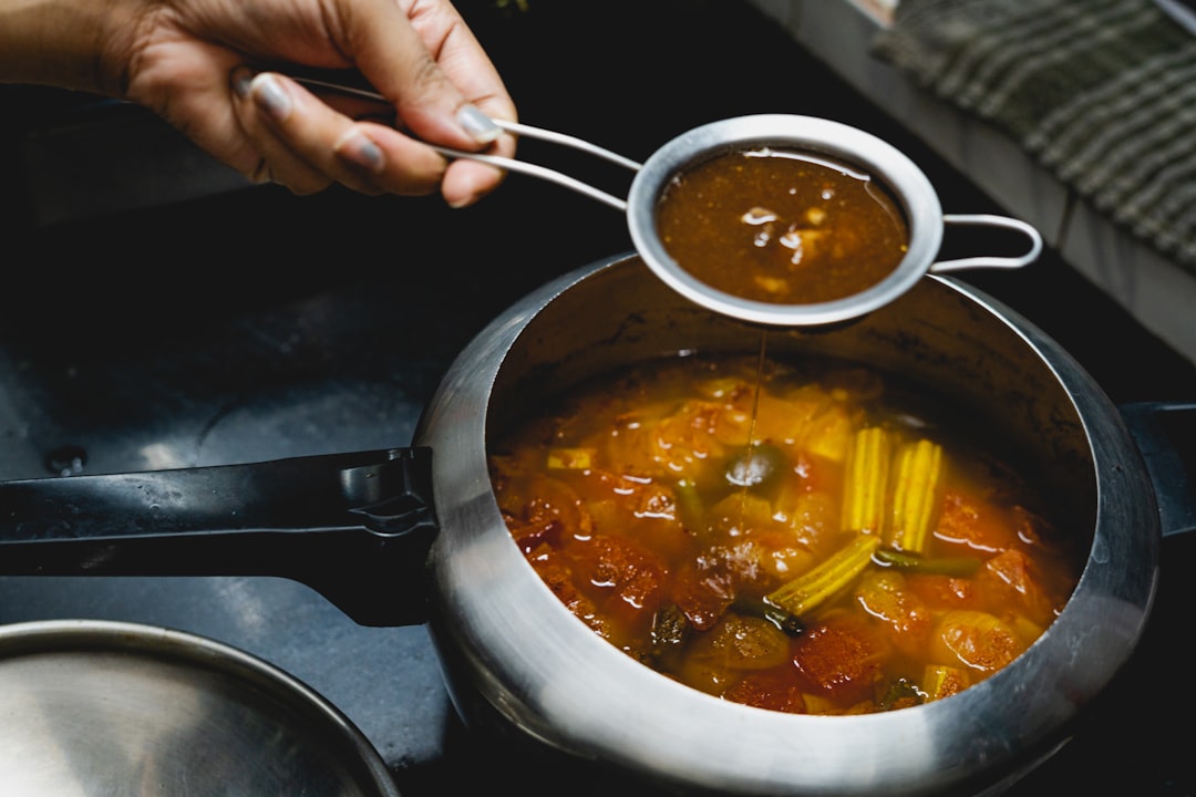 A home cook adding a splash of aged vinegar to a simmering pot on a stovetop