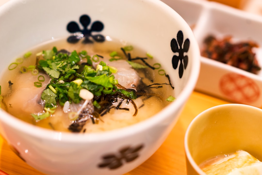 Un cocinero casero revuelve pasta de miso fermentada en un caldo a base de plantas creando sabor profundo sin carne ni caldo.