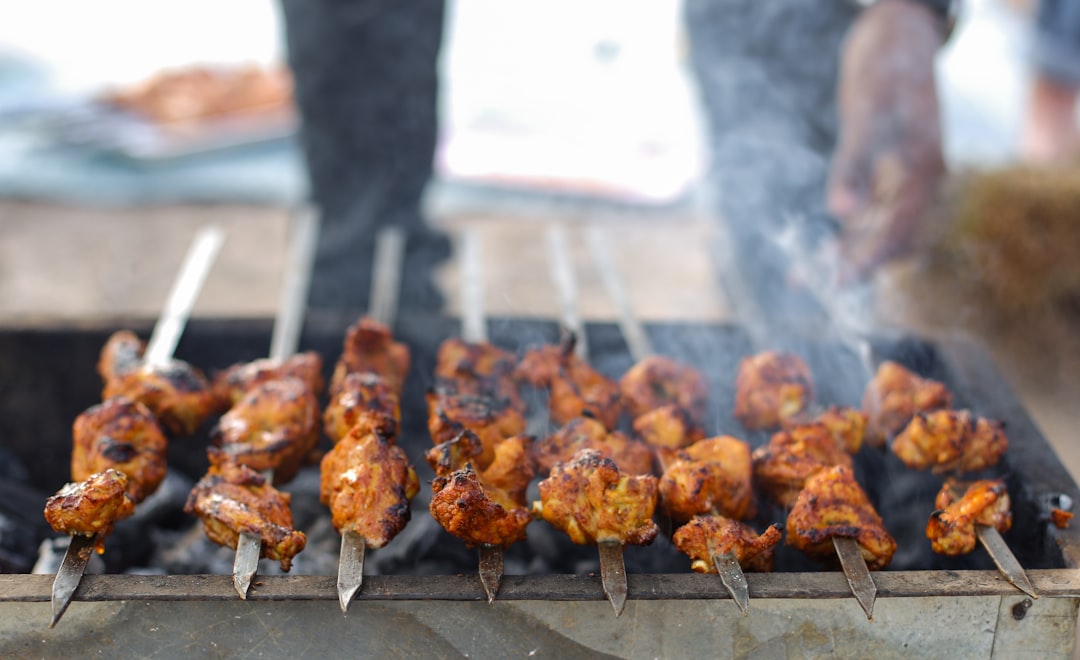 A person grilling protein that has been prepared using marinade basics on a charcoal grill