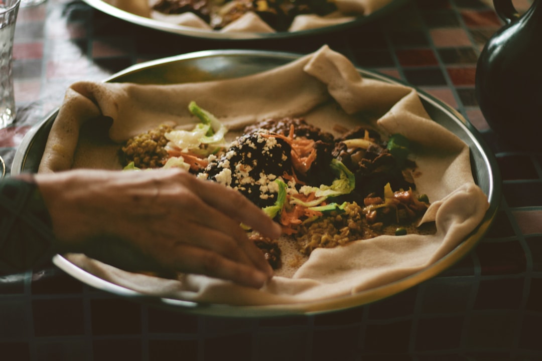 A person placing a bowl of chilled grain salads on a summer dining table set with fresh herbs and lemon