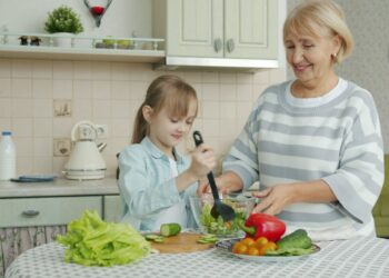 woman-cooking-salad-unsplash - GUSTOwebzine A woman carefully dressing chilled grain salads in a bright kitchen, showcasing global culinary technique