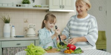 woman-cooking-salad-unsplash - GUSTOwebzine A woman carefully dressing chilled grain salads in a bright kitchen, showcasing global culinary technique