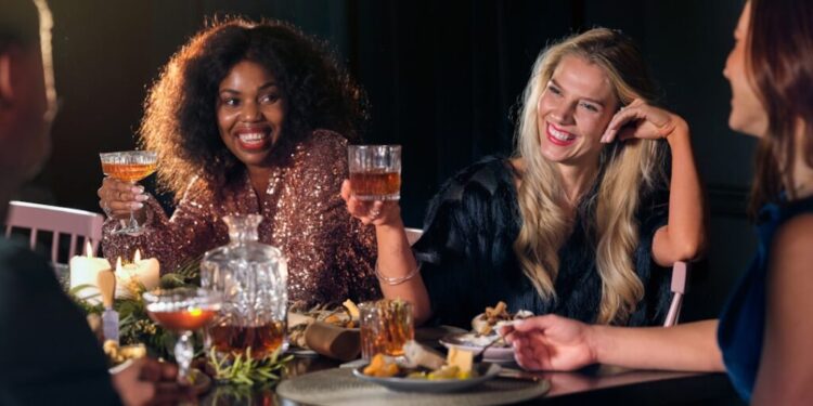 Members-only dining clubs in Dubai - GUSTOwebzine Group of friends at a candlelit dinner raising glasses in a cheerful toast, mid-conversation smile.
