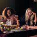 Group of friends at a candlelit dinner raising glasses in a cheerful toast, mid-conversation smile.