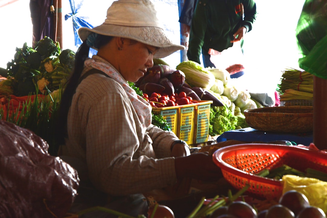A woman carefully selecting seasonal vegetables at a market to support Mediterranean cooking at home