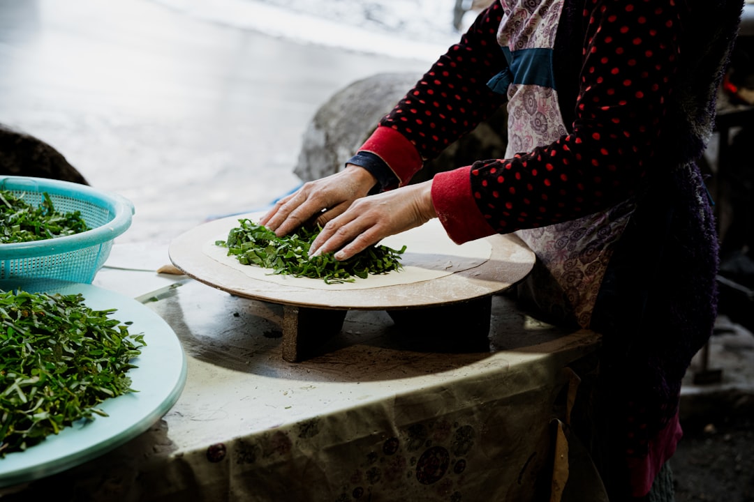 A woman grinding cilantro and garlic in a mortar to make a traditional green sauce from scratch