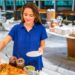 Gluten-free buffet guide for Dubai - GUSTOwebzine A woman in a blue shirt serves breakfast at a buffet, placing croissants and jars of jam on the table.