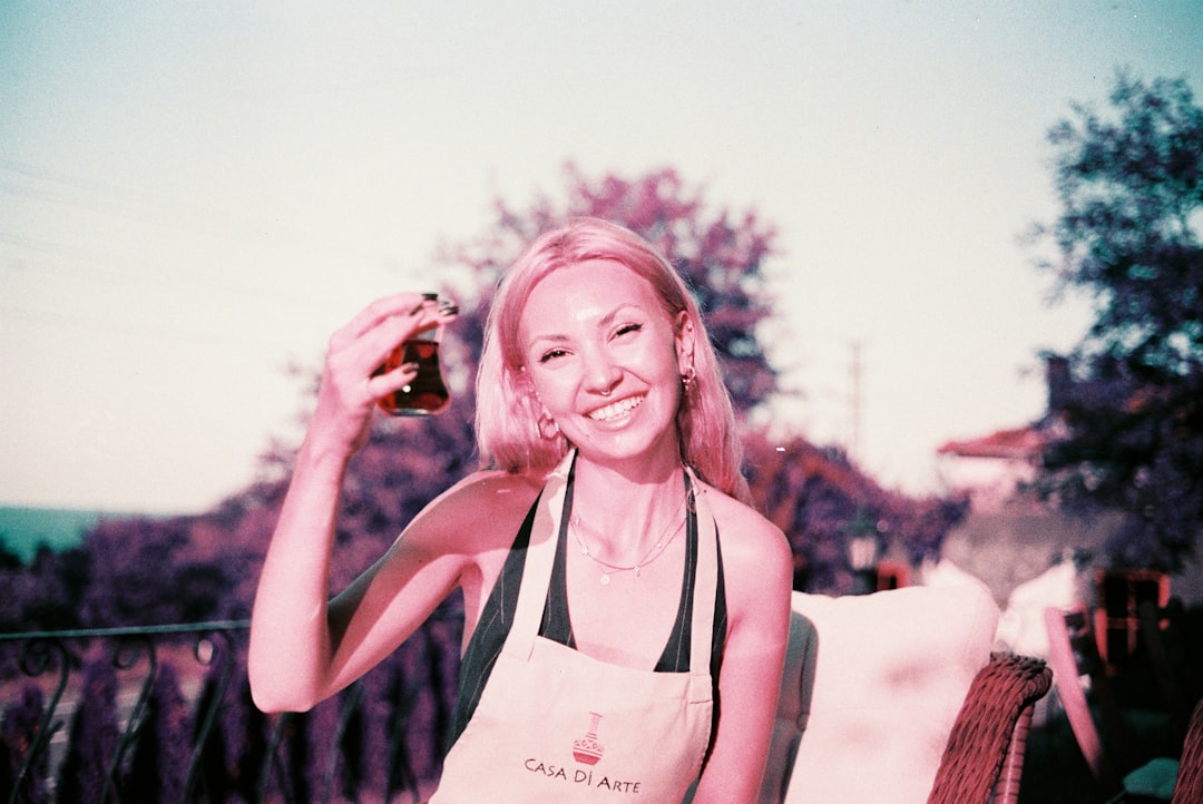 A woman sampling aged vinegar at a specialty food market stall surrounded by artisan bottles