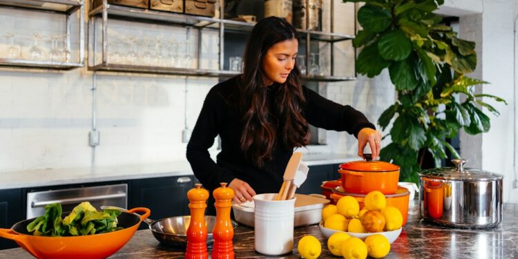 a woman arranges roasted root vegetables on a plate as part of the new autumn menus service in a kitchen.