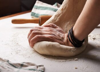 Een bekwame bakker die met de hand een zuurdesembrood vormt, wat het ambacht in de kern van wereldwijde broodtradities weerspiegelt