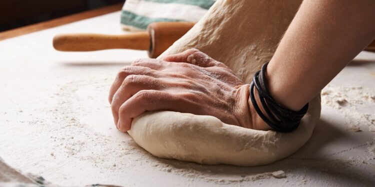 bakker-vormt-zuurdesembrood-unsplash - GUSTOwebzine Een bekwame bakker die met de hand een zuurdesembrood vormt, wat het ambacht in de kern van wereldwijde broodtradities weerspiegelt