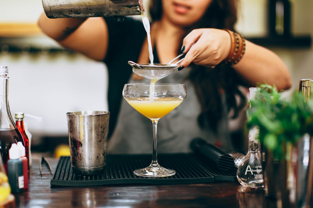 A bartender presents a freshly made pressed juice drink in a warm autumn setting