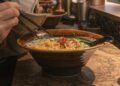 Ramenrestaurants in Londen gids voor de beste kommen - GUSTOwebzine Een kom ramen op een marmeren tafel, gegarneerd met groenten en rode chilidraadjes, waarbij stokjes noedels omhoog tillen en een lepel in de kom rust.