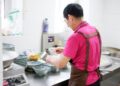 A chef carefully building an aromatic base in a pot, preparing a classic one-pot rice dish with layered spices and stock.