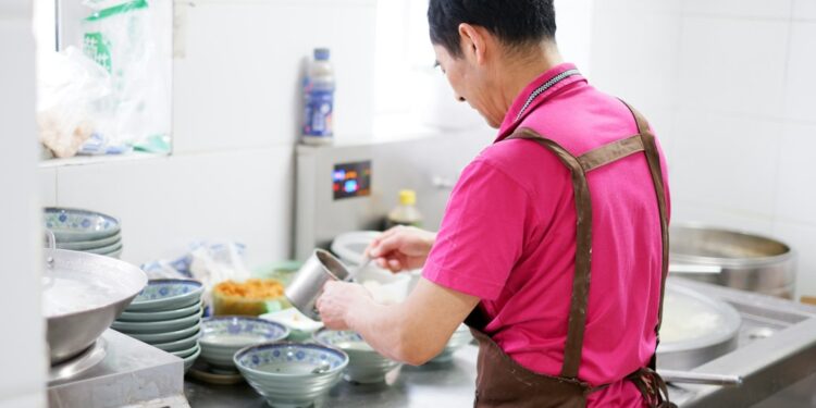 A chef carefully building an aromatic base in a pot, preparing a classic one-pot rice dish with layered spices and stock.