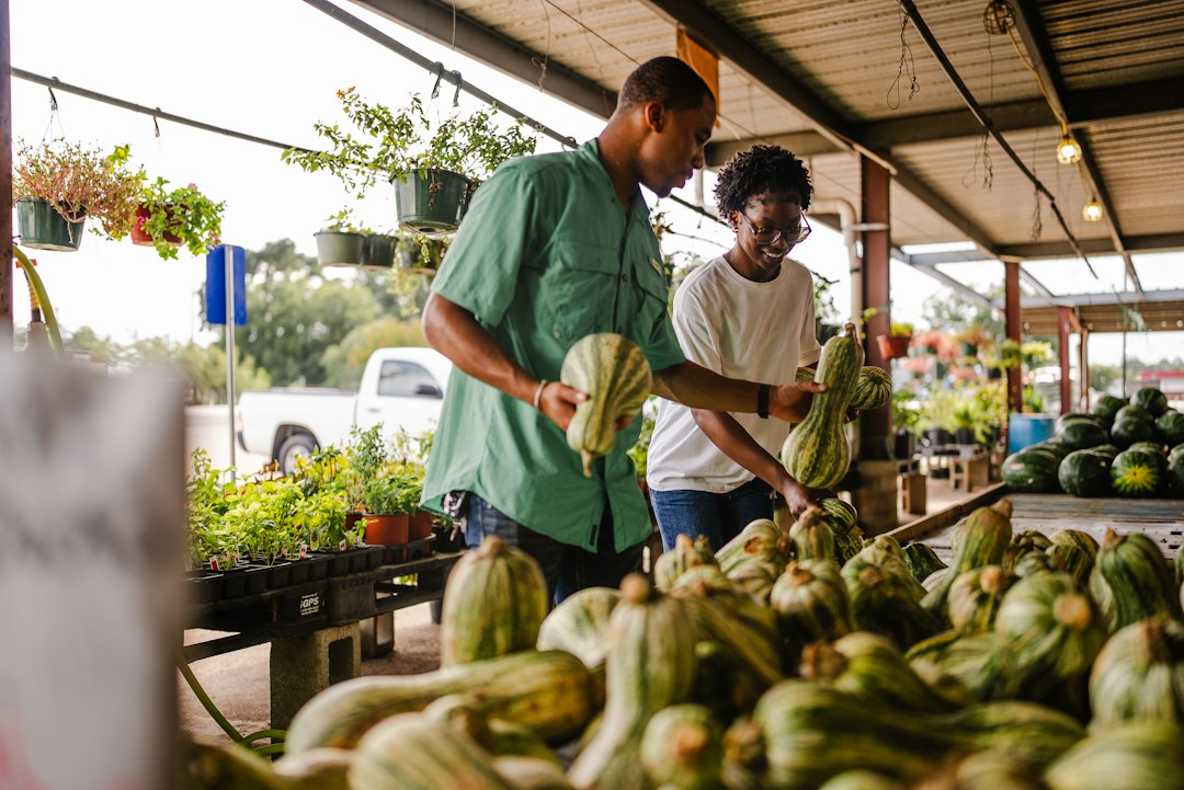 Een kok die zorgvuldig winterpompoen selecteert op een oogstmarkt, wat de verschuiving in seizoensingrediënten tijdens de herfstequinox weerspiegelt
