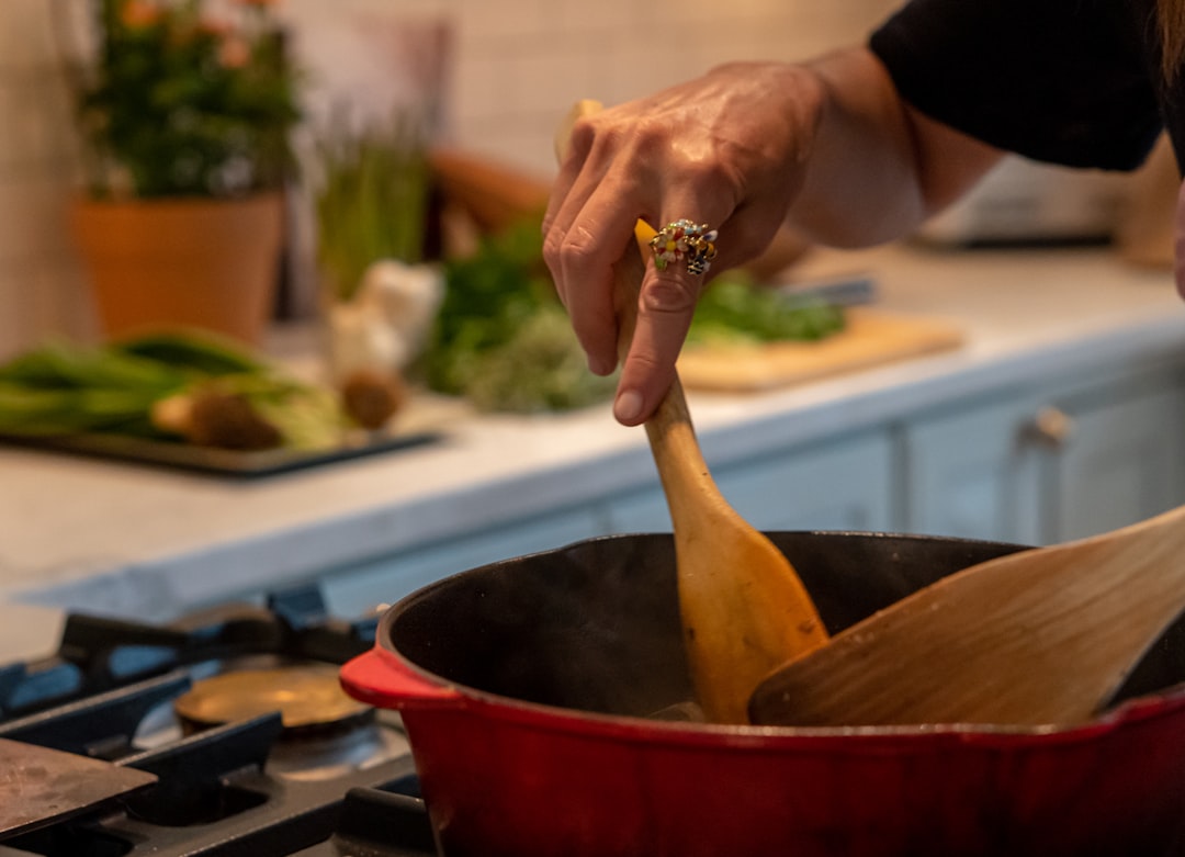 A home cook stirring aromatics in a skillet while preparing a pan sauce on a stovetop