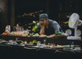A hotel dining team member tastes a new dish during a pre-service training session, building ingredient knowledge.