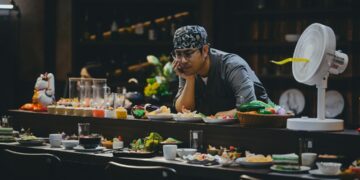 A hotel dining team member tastes a new dish during a pre-service training session, building ingredient knowledge.