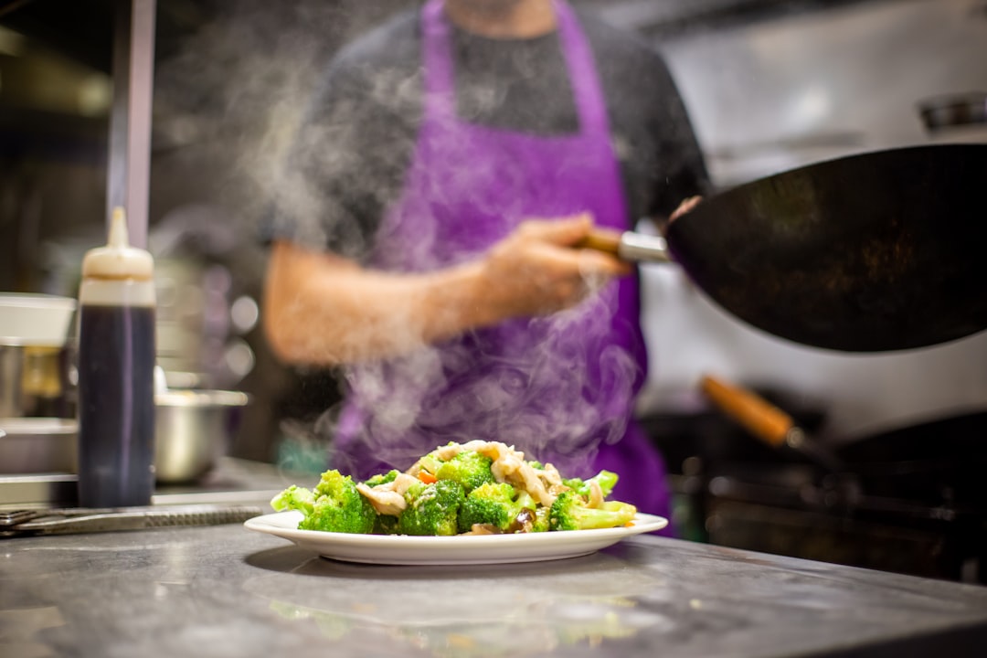 Een man die wereldse smaakmakers toevoegt aan een kleurrijk roerbakgerecht in een wok in de keuken
