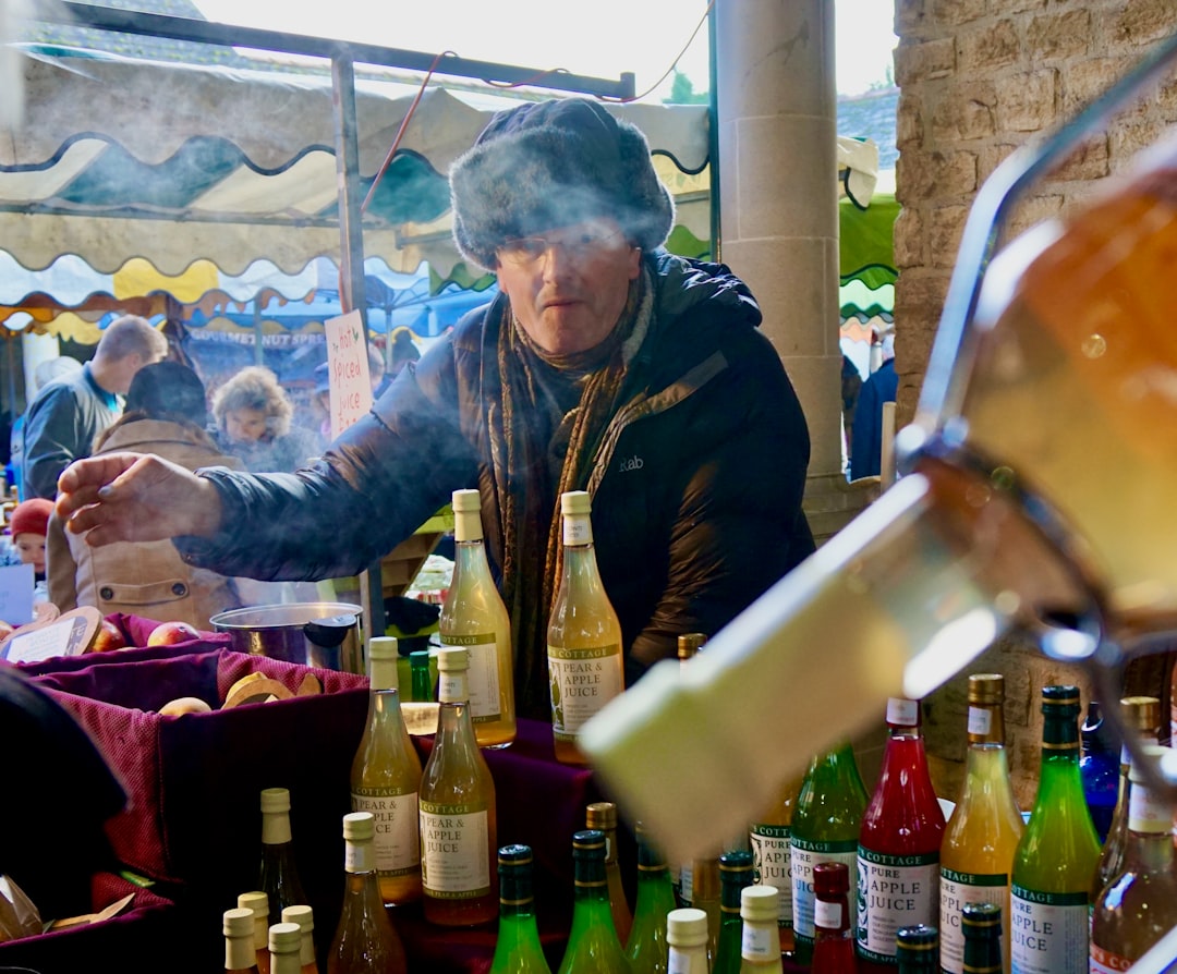 Een persoon wikkelt beide handen om een kop warme gekruide dranken op een wintermarkt, wat de diepe Europese traditie weerspiegelt.
