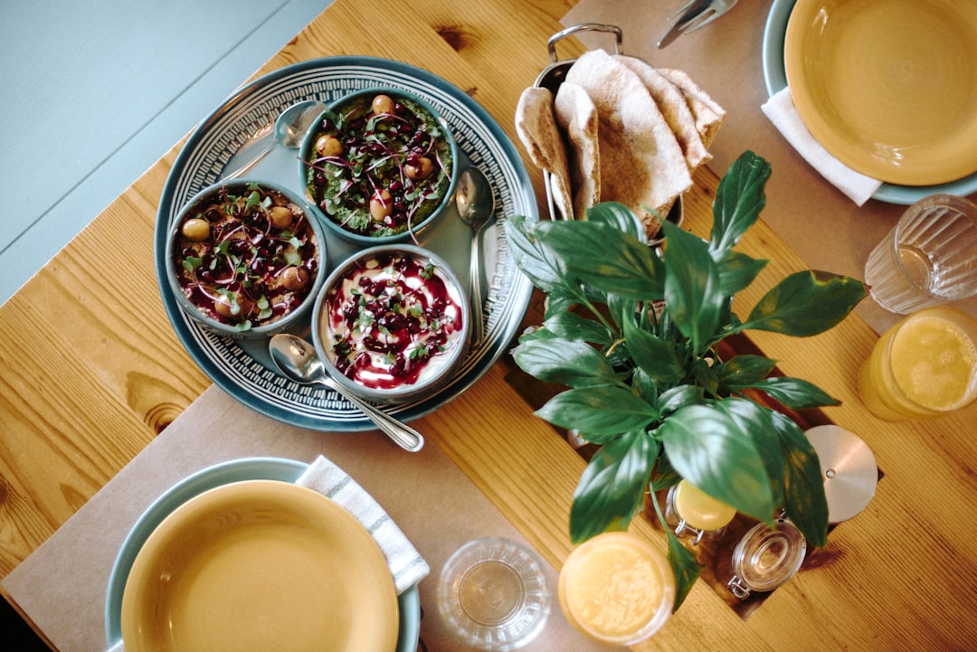 Iemand schept langzaam gegaarde bonen in een kom aan een prachtig gedekte eettafel, klaar om te eten