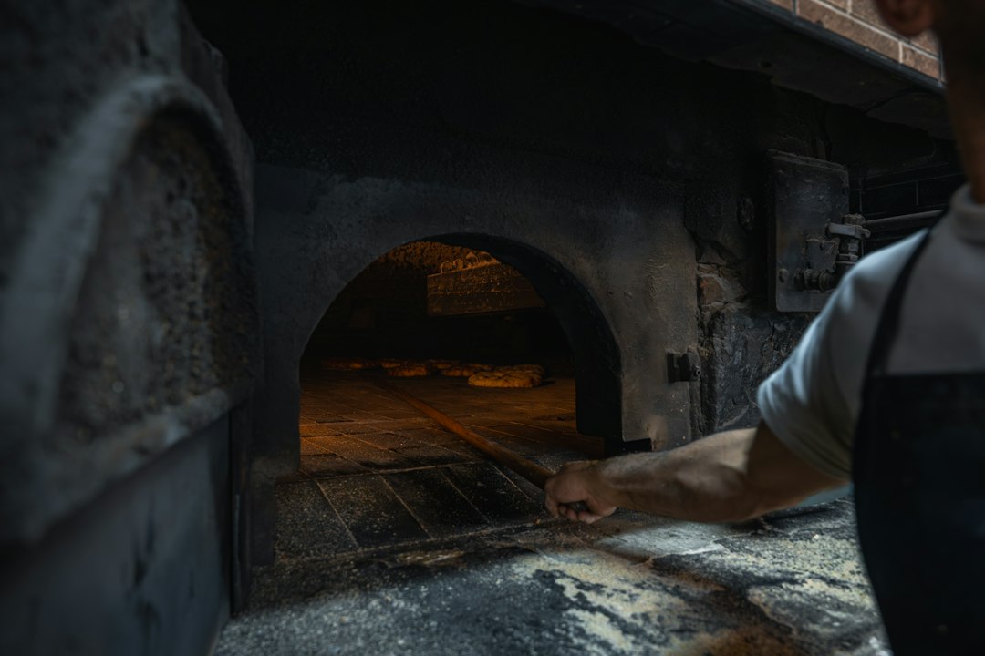 A baker working at a traditional stone oven, practicing bread traditions that have endured across cultures and centuries