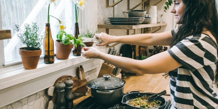 A home cook carefully stirring a warm grain dish in a large pot, surrounded by seasonal root vegetables on a kitchen counter