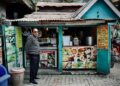 Hygiene grades what they mean before you eat - GUSTOwebzine Man in a striped sweater stands at a teal roadside snack stand offering milkshakes and cones, facing the camera.