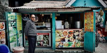 Hygiene grades what they mean before you eat - GUSTOwebzine Man in a striped sweater stands at a teal roadside snack stand offering milkshakes and cones, facing the camera.