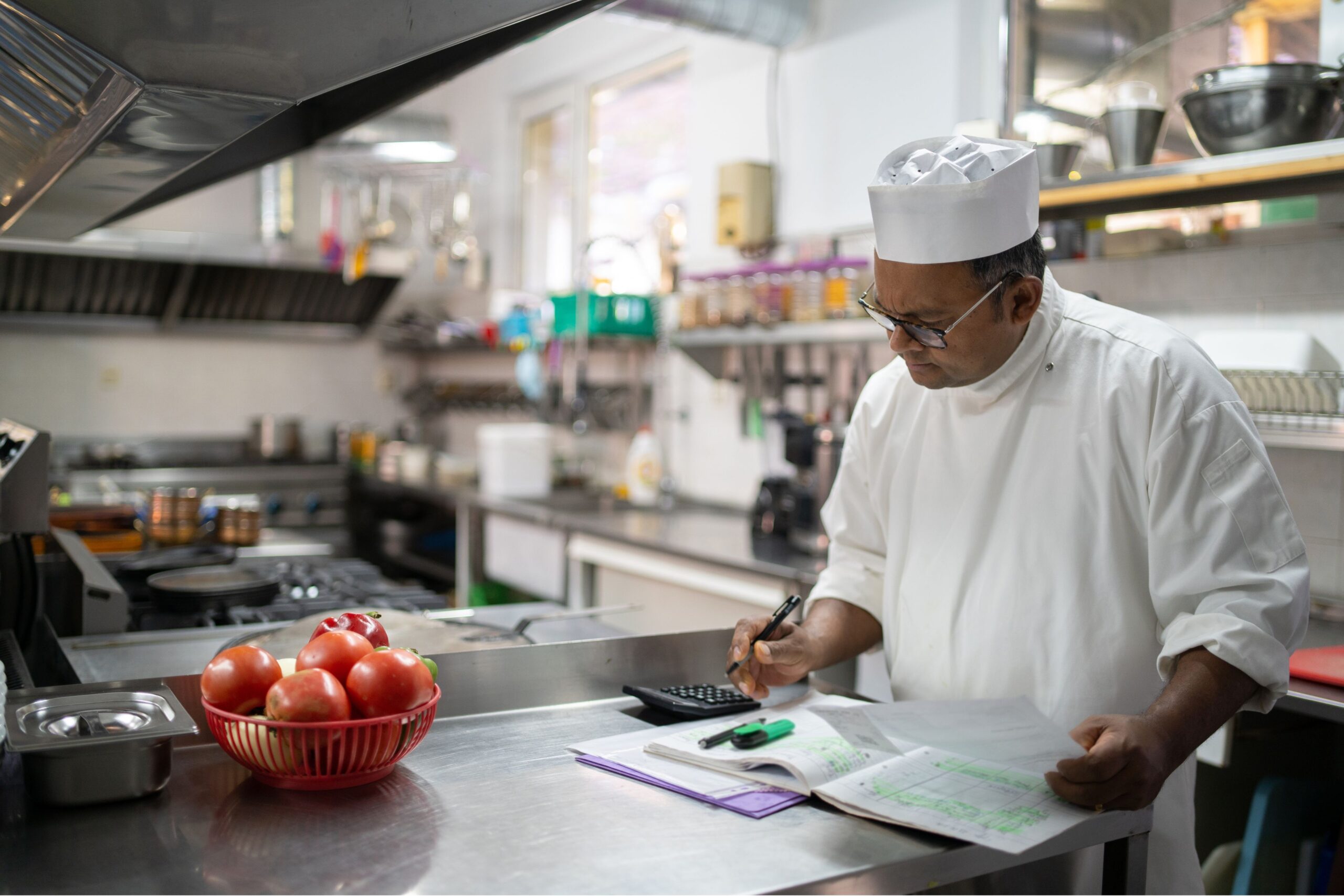 Professional chef calculating food cost in commercial restaurant kitchen